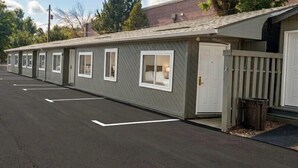 A row of motel-style buildings with individual rooms, a parking lot, and a gated entrance. - Renovated Queen Room on Main Street in Longmont (Longmont)