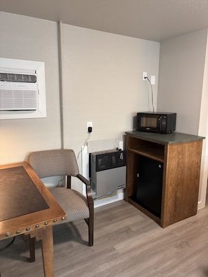 Una kitchenette compacta con microondas, una silla y una mesa.