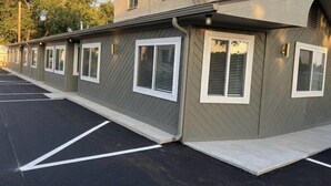 A row of motel rooms with individual entryways, a parking lot, and a building exterior. - Renovated Queen Room on Main Street in Longmont (Longmont)