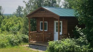 Eine kleine Holzhütte mit Veranda, umgeben von dichtem Grün.