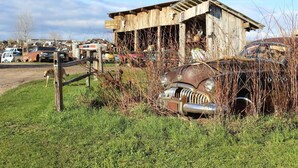 Ein verlassenes Gebäude mit einer baufälligen Struktur und einem Oldtimer im Vordergrund.