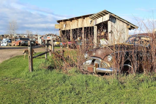 Un edificio abandonado con una estructura deteriorada y un coche antiguo al frente.