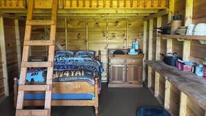 Ein Holzhäuschen im Inneren mit Schlafzimmer auf Hochbett, einer Küchenzeile und einem Platz für ein Haustier.