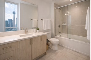 Une salle de bain moderne avec un grand miroir, un lavabo, des toilettes et une douche à parois de verre.