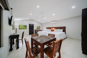 A hotel room with a bed, a desk, and a dining table with chairs. - Deluxe family Bedroom - Beachfront - Manuel Antonio with AC (Manuel Antonio)