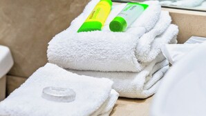A bathroom with stacked white towels and green and yellow bottles on them. - Deluxe family Bedroom - Beachfront - Manuel Antonio with AC (Manuel Antonio)