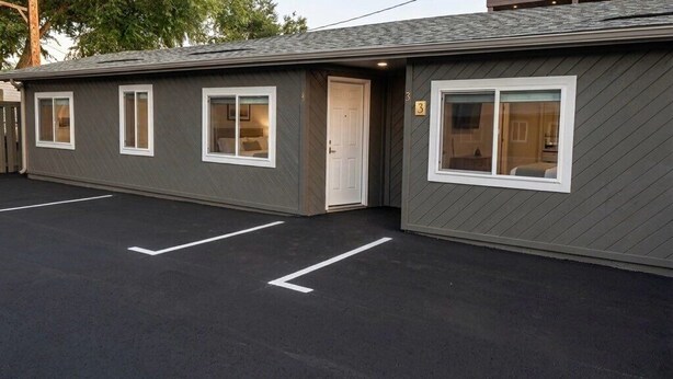 A motel with a parking lot, a single-story building, and a door.