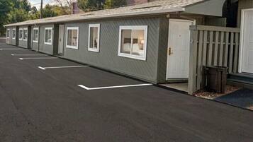 Une rangée de bâtiments de type motel, avec des chambres individuelles, un parking et une entrée fermée par un portail.