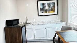 A kitchen with white cabinets, a microwave, a sink, and a dining table with chairs.