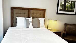 A neatly made bed with a wooden headboard, a bedside lamp, and a framed picture on the wall.
