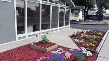 Un bâtiment doté de grandes fenêtres, une enseigne indiquant « LONGMONT », et un espace paysager agrémenté de parterres de fleurs.