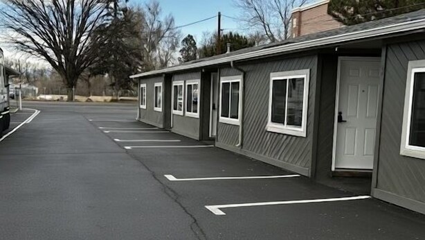 A row of motel rooms with individual doorways and a parking lot. - Large Renovated Double Queen Studio (Longmont)