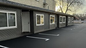 A row of single-story buildings with a parking lot in front. - Large Renovated Double Queen Studio (Longmont)