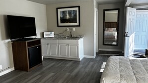 A bedroom with a bed, a television, a microwave, and a sink. - Large Renovated Double Queen Studio (Longmont)
