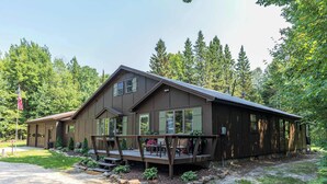 A two-story cabin with a porch, surrounded by trees.