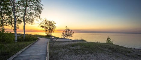 A wooden boardwalk leading to a beach with a sunset view.