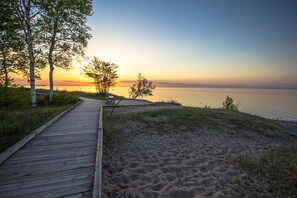 En träpromenad som leder till en strand med utsikt över solnedgången.
