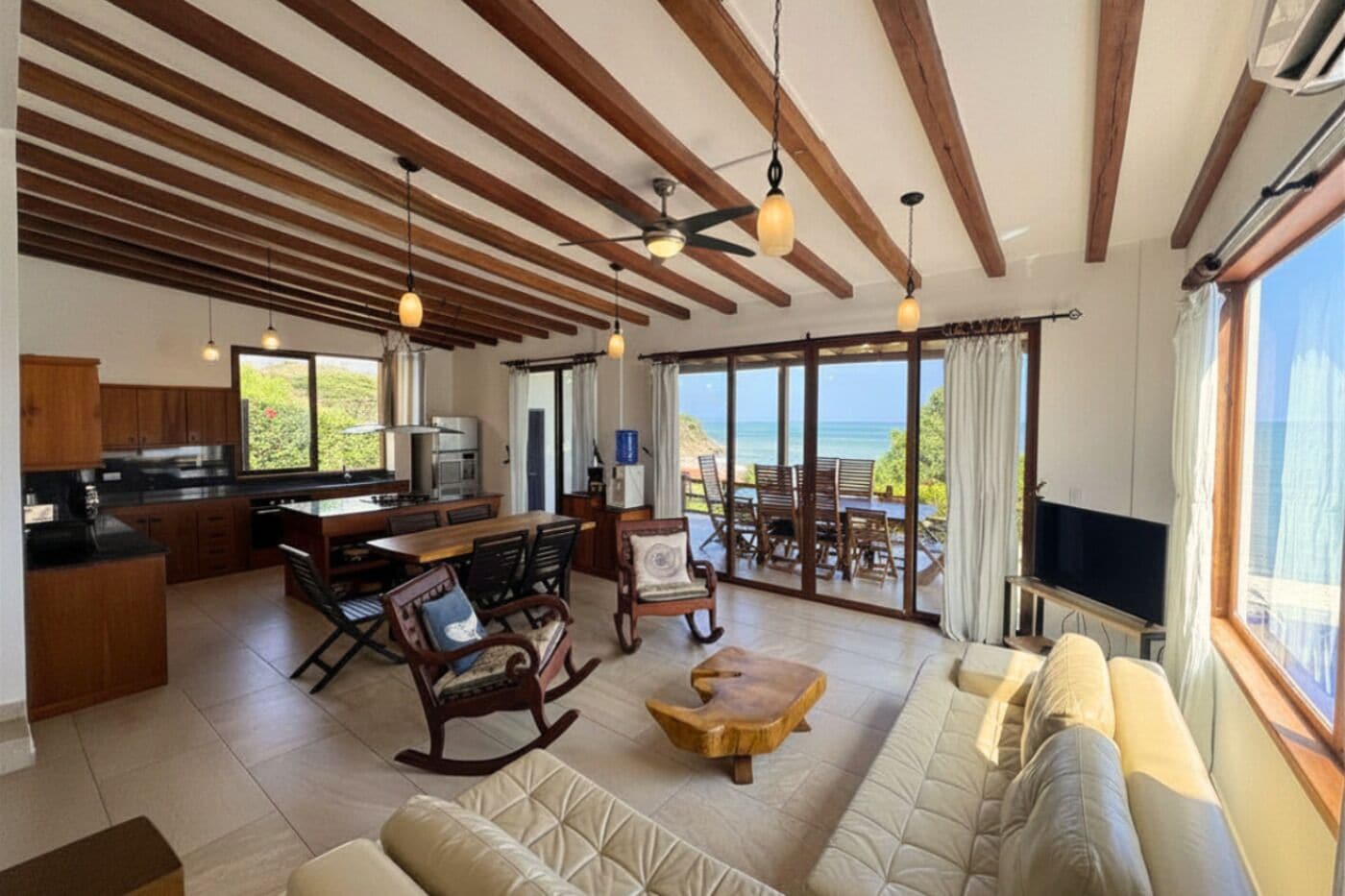 A spacious living area with a kitchen, dining area, and a balcony with a view.