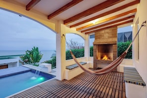 A poolside area with a hammock, a fireplace, and a view of the ocean. - Jama Campay Villas by Otium (Jama)