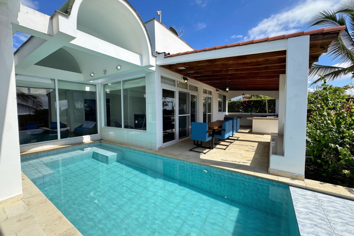 Uma casa moderna com piscina, área de estar coberta e grandes janelas.