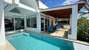 Uma casa moderna com piscina, área de estar coberta e grandes janelas.