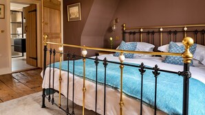 Ein Schlafzimmer mit einem Bett, Holzbalken, einem Bild an der Wand und einer Tür zu einem anderen Raum.