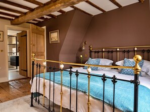 Ein Schlafzimmer mit einem Bett, Holzbalken, einem Bild an der Wand und einer Tür zu einem anderen Raum.