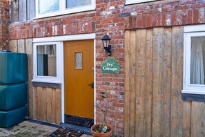 A brick building with a wooden door, a window, and a sign that reads 'Ivy Cottage.' - Cottage With En-suite Bedrooms (Exeter)