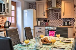 A kitchen with a dining table set for breakfast, including bread, butter, and orange juice. - Cottage With En-suite Bedrooms (Exeter)