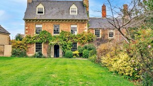 A two-story brick house with a symmetrical facade, a central entrance, and a well-maintained lawn. - Cotswolds Manor With Garden (Lechlade)