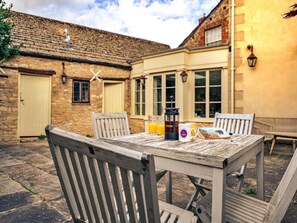 Eine Terrasse im Freien mit Holztisch und -stühlen, einer Kaffeemaschine und einer Tasse.