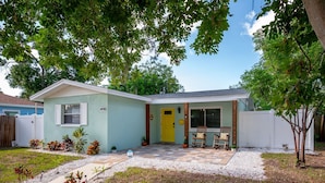 A single-story house with a yellow front door, a small porch with two rocking chairs, and a mailbox. - Lemon Door Cottage (St. Petersburg)