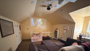 Ein gemütliches Wohnzimmer mit Deckenprojektor, Basketballkorb und Bücherregal.