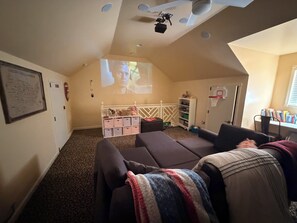 Ein gemütliches Wohnzimmer mit Deckenprojektor, Basketballkorb und Bücherregal.