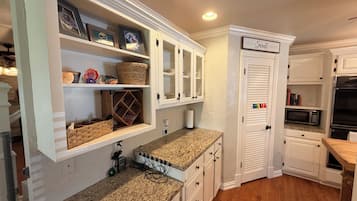A kitchen with white cabinetry, a granite countertop, and a sign that reads 'HOME Sweet HOME'.