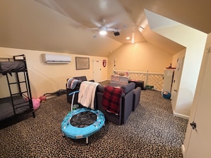 A room with a bunk bed, a trampoline, a sofa, and a small play area.