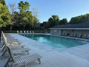 Ein Schwimmbecken mit Liegestühlen und einer überdachten Liegefläche.