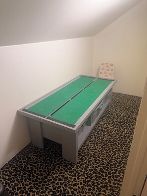 Una habitación pequeña con un tapete de juego verde, una pared blanca y una alfombra de estampado de leopardo.