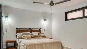 A bedroom with a bed, a ceiling fan, bedside lamps, and a window. - Modern Oasis 2BR Condo/ Walk to Camarones Beach & Malecón (Puerto Vallarta)