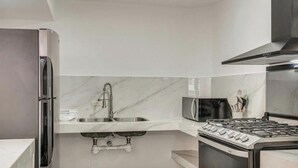 A modern kitchen with a stainless steel refrigerator, a double sink, a microwave, and a gas stove. - Modern Oasis 2BR Condo/ Walk to Camarones Beach & Malecón (Puerto Vallarta)