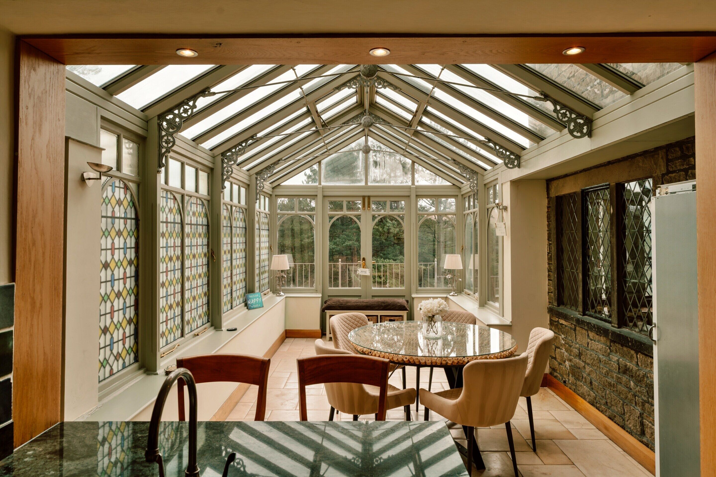 A conservatory with a glass ceiling, a round table, and four chairs.