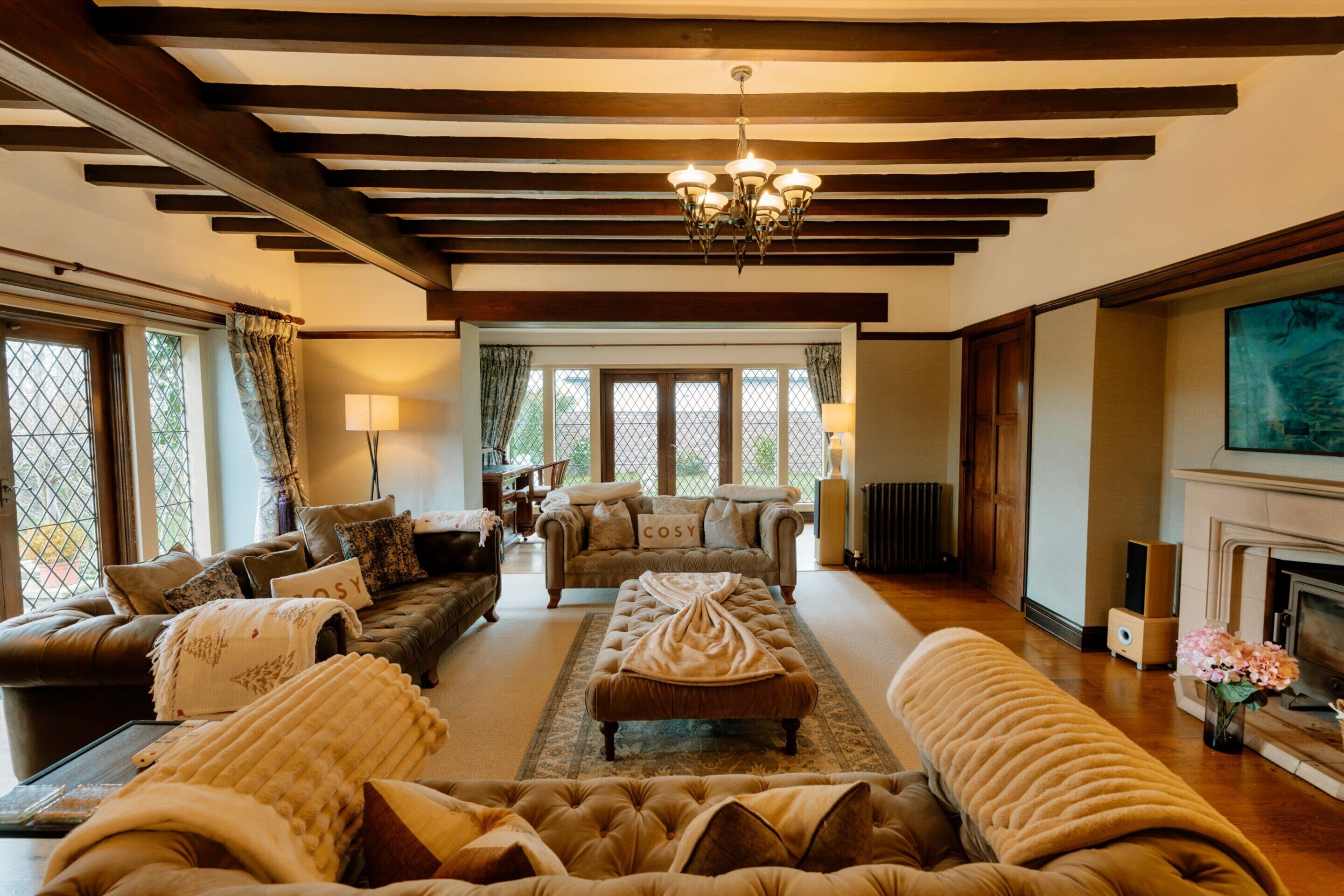 A spacious living room with a fireplace, multiple seating areas, and large windows allowing natural light.