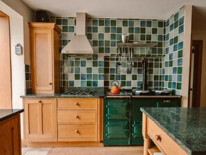 A kitchen with wooden cabinets, a stove, and a green dishwasher. - Holiday Home With Lyme Park Views (Stockport)