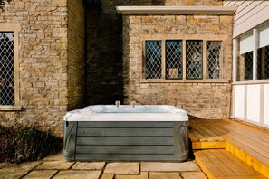 Ein Wellnessbereich mit Whirlpool, Steinwänden und einer Holzterrasse.