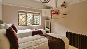 Ein Schlafzimmer mit zwei Betten, einem Fenster mit Aussicht, einem Heizkörper und einem Schild mit dem Schriftzug 'VIBES'.
