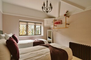 Ein Schlafzimmer mit zwei Betten, einem Fenster mit Aussicht, einem Heizkörper und einem Schild mit dem Schriftzug 'VIBES'.