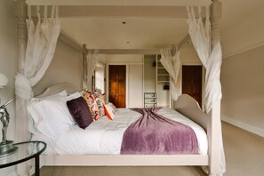 A four-poster canopy bed with a white headboard, multiple pillows, and a purple throw blanket. - Holiday Home With Lyme Park Views (Stockport)