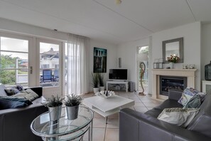 Ein modernes Wohnzimmer mit Kamin, Fernseher und einer Sitzecke.