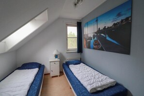 Un dormitorio pequeño con una cama doble, una ventana, un radiador y un cuadro en la pared.