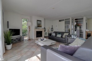 Una sala de estar moderna con chimenea, televisor y sofá.
